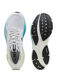 Zapatillas deportivas blancas para correr con entresuelas de degradado azul y amarillo, parte superior de tela de malla y suelas exteriores negras con dibujo, mostradas desde vistas superior e inferior.