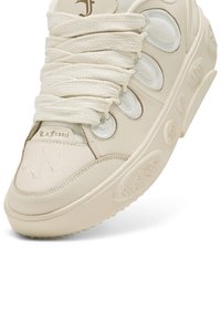 Krämfärgad sneaker av läder och nät. Har tjocka snören, präglade detaljer och en kraftig sula med texturerat grepp.