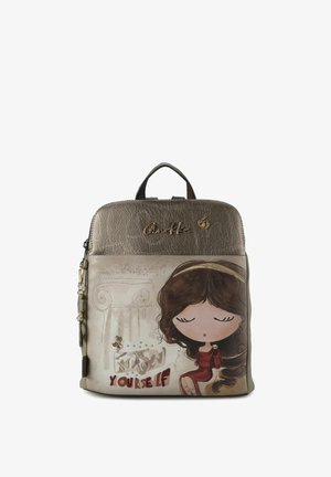 Zaino in materiale dorato testurizzato con disegno di una ragazza in stile cartone animato. Presenta una maniglia superiore, chiusura con cerniera e dettagli decorativi.