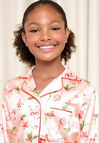 Sidenlena rosa pyjamasset med julmotiv, med röda och gröna accenter, dekorativa knappar och en bröstficka.