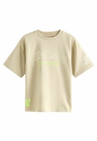 T-shirt en coton beige à manches courtes, avec un graphique "NEW YORK" en texte blanc et vert néon, et un petit logo sur la manche.