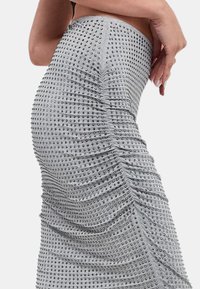 Gonna grigia con design aderente e trama arricciata, decorata con borchie argento distribuite su tutta la superficie, che evidenzia una silhouette aderente.