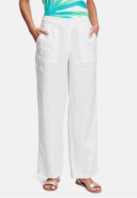 White linen wide-leg pants with front patch pockets, featuring a relaxed fit and soft texture. Paired with light metallic sandals.