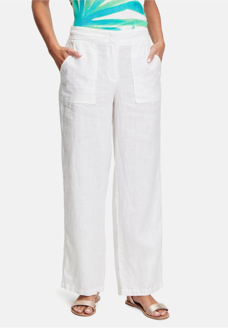 White linen wide-leg pants with front patch pockets, featuring a relaxed fit and soft texture. Paired with light metallic sandals.