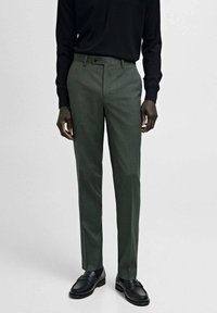 Mörkgröna skräddarsydda byxor med en slät yta, rak front och bälteöglor, kombinerat med svarta loafers och en åtsittande svart topp.