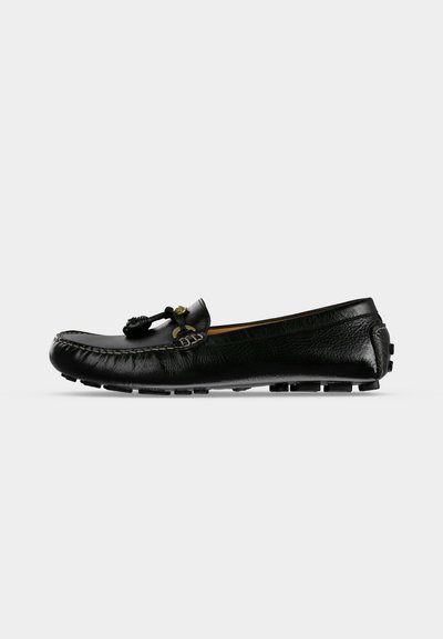Mocassin en cuir noir avec détail de lacets à pompons et semelle en caoutchouc, présenté en profil sur un fond clair uni.