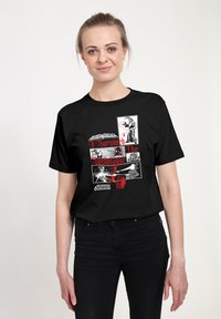 Žena v černém tričku s designem Dungeons & Dragons, který obsahuje kostky, kouzelníka a text "Přežila jsem Spellplague."