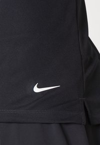 Črno teksturirano blago z belim logotipom Nike swoosh blizu spodnjega roba in majhnim stranskim razporkom na robu.