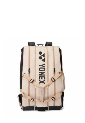 Sac à dos Yonex beige et noir avec plusieurs compartiments zippés verticaux et sangles avant réglables.