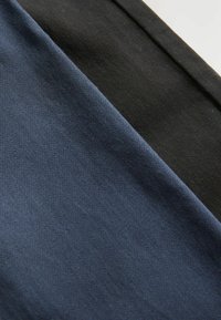 Stoffmuster in Dunkelblau und Schwarz, die eine glatte, strukturierte Oberfläche mit einem leichten Glanz zeigen. Am oberen Rand sind die Nähte sichtbar.