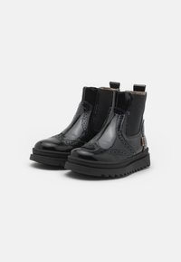 Botine din piele lăcuită neagră, cu design brogue, panouri laterale elastice și o talpă din cauciuc masiv, cu un model de profil în zigzag.
