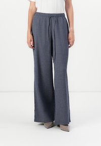 Pantalon à jambes larges en tissu texturé, doté d'une taille à cordon de serrage de couleur bleu foncé, avec une coupe décontractée et des fentes latérales.