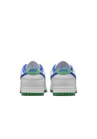Paire de baskets blanches Nike vues de dos, avec des languettes de talon vertes portant des logos Nike bleus, une doublure intérieure bleue et des semelles vertes.