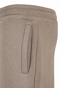 Beige joggebukser med en myk tekstur, elastisk liv, og sidelommer med et enkelt design.
