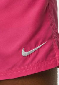 Pantaloni sportivi leggeri di colore rosa, realizzati in tessuto morbido, con il logo Nike ricamato in argento sul lato sinistro, caratterizzati da cuciture pulite e una texture liscia.