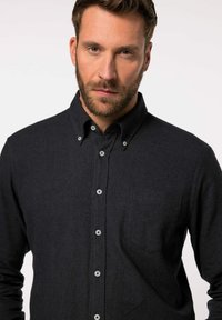 Mørkeblå skjorte med knapper, lavet af tekstureret stof, med krave, en enkelt lomme og sølvknapper langs fronten.