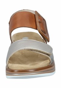 Brown leather ankle strap sandal with silver band and rectangular buckle, cushioned beige insole, and white rubber sole.