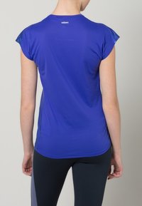 Blue athletic shirt with short sleeves, smooth texture, and a fitted design. Features a logo at the back neckline.