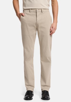 Beige cotton chinos with a straight-leg design, featuring a front button closure, side pockets, and a smooth texture. Black shoes complete the look.