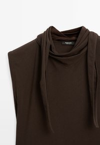 Brun langærmet top med draperet cowl-udskæring. Lavet af blødt stof, med en afslappet pasform og minimale designelementer.