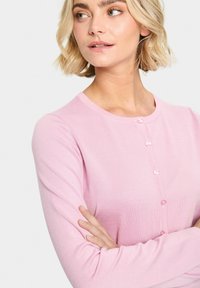 Roza rebrasta kardigan z dolgimi rokavi in okroglo ovratnikom, s šestimi usklajenimi gumbi spredaj. Mehka tekstura in prilegajoč slog.