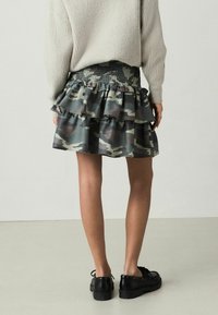 Jupe camo à niveaux avec ourlet froncé, dotée d'une taille élastiquée. Fabriquée dans un tissu léger aux teintes de vert, marron et gris.