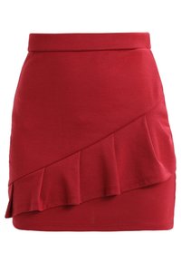 Röd stickad minikjol med en åtsittande midja, med en diagonalt volangdetalj längs ena sidan och en slät yta.