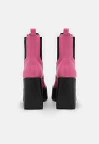 Botines de cuero rosa con paneles laterales de elastano negros, tacones cuadrados gruesos y tiradores, que ofrecen un contraste elegante en el diseño.