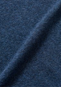 Gros plan sur un tissu tricoté bleu foncé doux et texturé avec de fines mailles régulières et un léger pli créant une ombre diagonale.