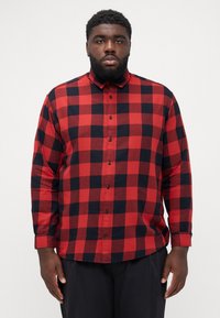 Camisa de cuadros roja y negra de botones con mangas largas, que presenta un collar y cierre de botones en la parte frontal. Material de algodón con una textura suave.