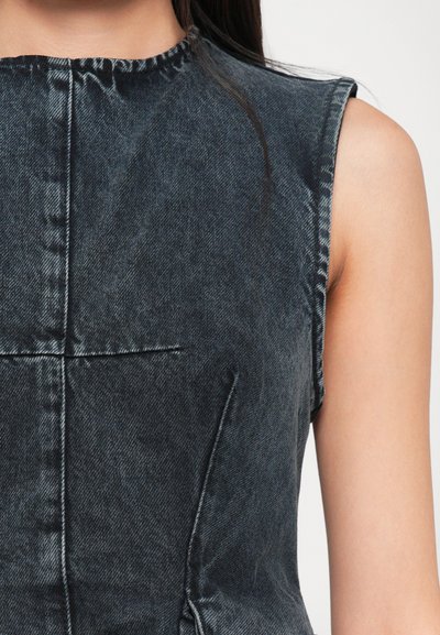 Melnā pelēkā nokrāsā bez piedurknēm izstrādāts denim topiņš ar gludu tekstūru, apļveida dekoltē un redzamām šuvju detaļām.