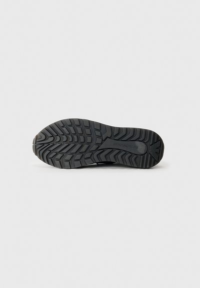 Black rubber shoe sole with textured tread patterns for traction, featuring a rounded toe and raised midsole for support.