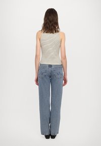 Canotta a righe con un design aderente, abbinata a jeans blu a vita alta e dalla vestibilità ampia con tasche posteriori e dettagli di cucitura discreti.