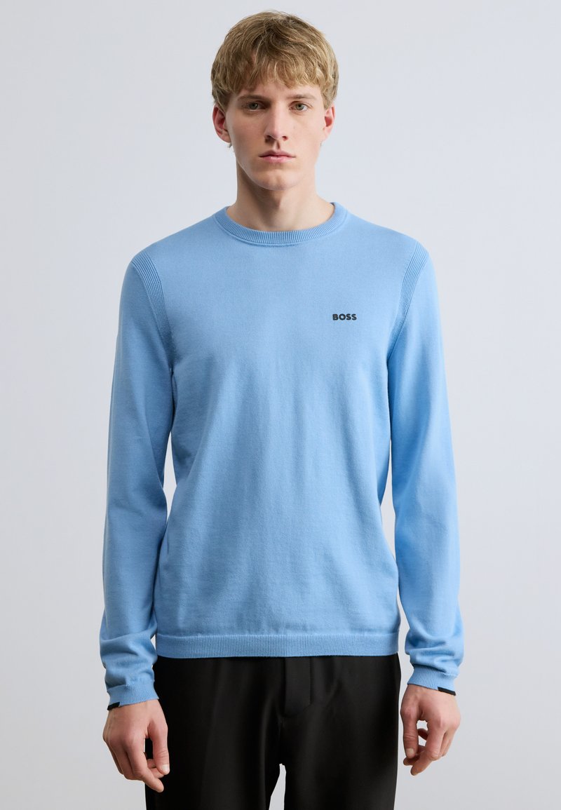 Világoskék póló hosszú ujjakkal és kerek nyakkivágással. Bordázott mandzsetta és szegély, a mellrészen pedig egy kis fekete "BOSS" logó található.