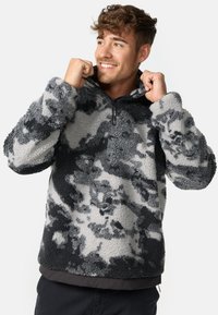 Sudadera de forro polar con cuello alto y media cremallera. Patrón de camuflaje en gris y negro, textura suave y puños elásticos.