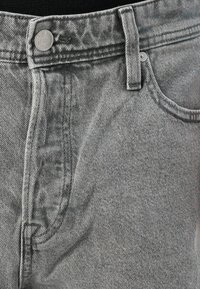 Jeans din denim gri au un design clasic cu cinci buzunare, închidere cu un buton și detalii subtile de cusătură. Materialul are o textură fină.