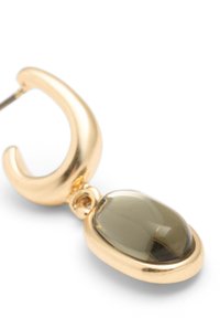 Guldörhänge med en oval olivgrön sten som är inbäddad i en slät bezel. Designen är stilren med en glänsande yta och böljande form.