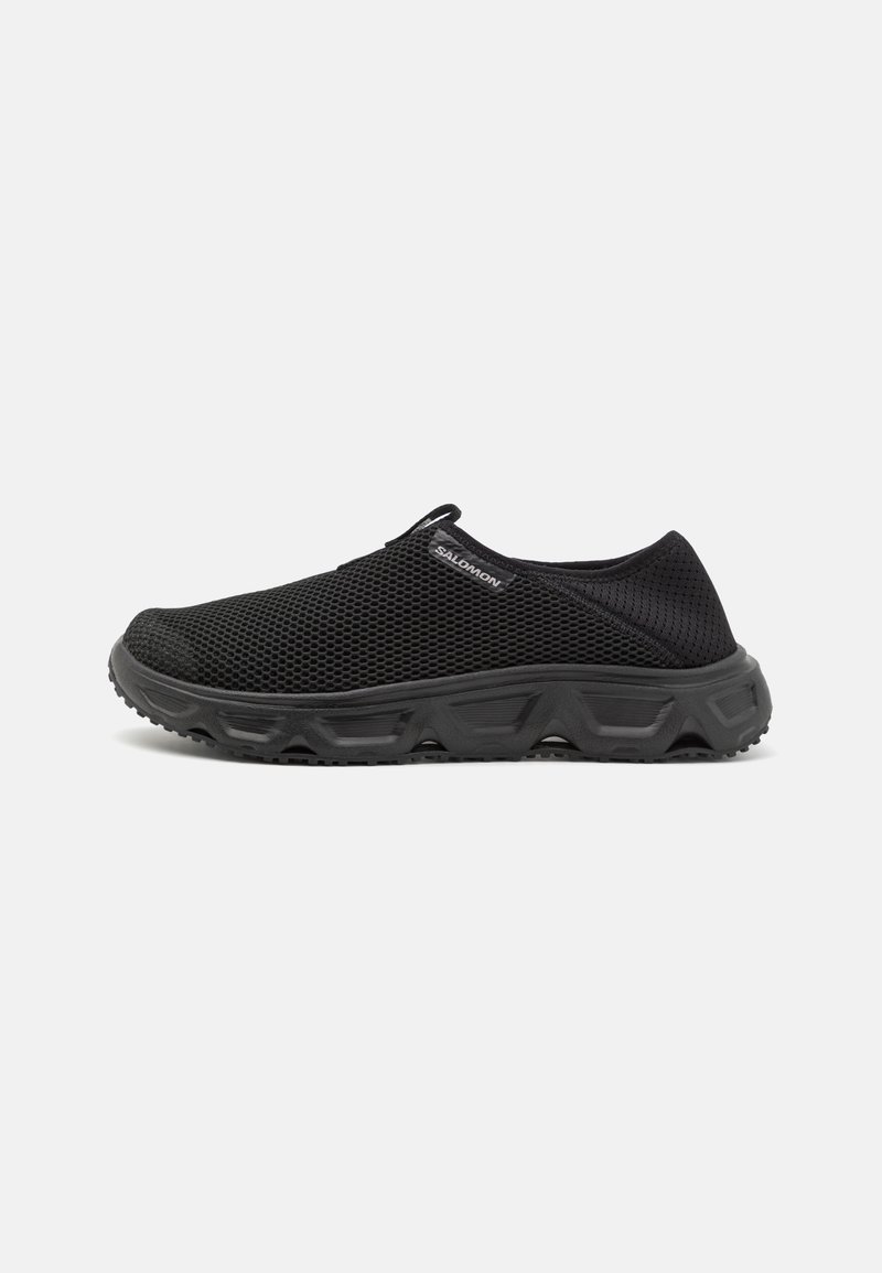 Sneakers noirs en mesh sans lacets avec une semelle épaisse texturée et une petite languette sur la languette, sur fond blanc uni.