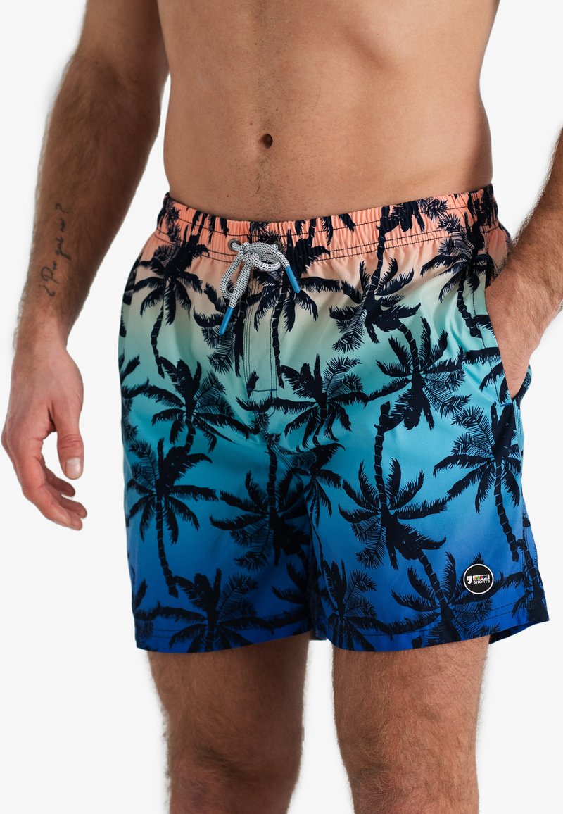 Shorts de bain avec un dégradé rose et bleu, présentant un motif de palmier, une taille élastique et un cordon de serrage. Fabriqués en matériau léger.