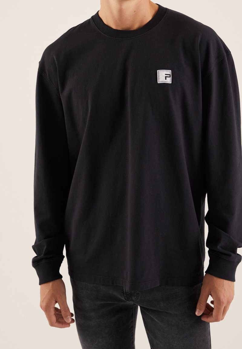 T-shirt a maniche lunghe nera in cotone, con collo rotondo e un piccolo logo rettangolare sulla parte sinistra del petto.