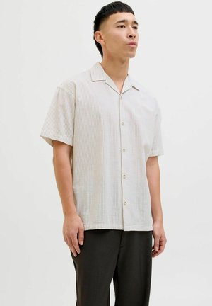Korte mouw gestreepte shirt in lichtbeige met verticale patronen, knoopsluiting en een ontspannen kraag; gecombineerd met donkere broeken.