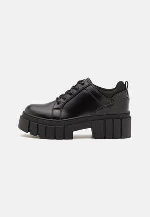 Czarne buty na platformie z gładką skórzaną cholewką, zaokrąglonym noskiem, sznurowanym zapięciem i grubą, rowkowaną podeszwą dla lepszej przyczepności.