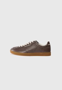 Sneaker in pelle marrone con punta arrotondata, lacci crema e suola in gomma color naturale. Presenta dettagli di cucitura e branding sul lato e sul tallone.