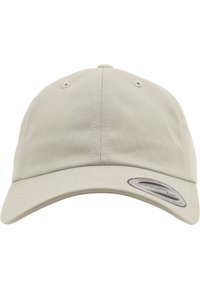 Tan baseballpet met een gebogen rand, gemaakt van gestructureerde stof, voorzien van ventilatiegaatjes en een ronde merklabel aan de zijkant.