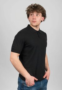 Svart kortärmad polo skjorta i ribbad trikå med klassisk krage, med en åtsittande design och mjuk struktur.