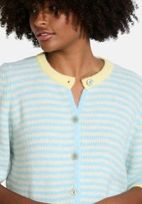 Light blue and cream striped cardigan with short sleeves, featuring a yellow collar and three button closures with transparent accents.