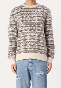 Stickad tröja i beige och brunt med geometriska mönster, rund halsringning, ribbade muddar och nederkant, lätt tyg och avslappnad passform.