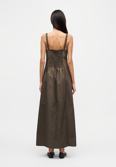 Καφέ, μακρύ, αμάνικο φόρεμα από λείο ύφασμα; διαθέτει πλισέ πίσω μέρος και λεπτές τιράντες; το τελείωμα φτάνει στους αστραγάλους.