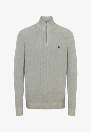 Svijetlosiva, rebrasta pletena majica s visokim ovratnikom i zatvaračem na pola. Ima mali grb na prsima te rebraste manžetne i rub.