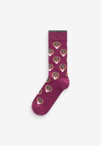 Bordeauxfarbene Socken mit grünem Bund, die wiederholte Muster von Pavian-Gesichtern in Braun, Blau und Weiß zeigen. Hergestellt aus weichem, dehnbarem Stoff.